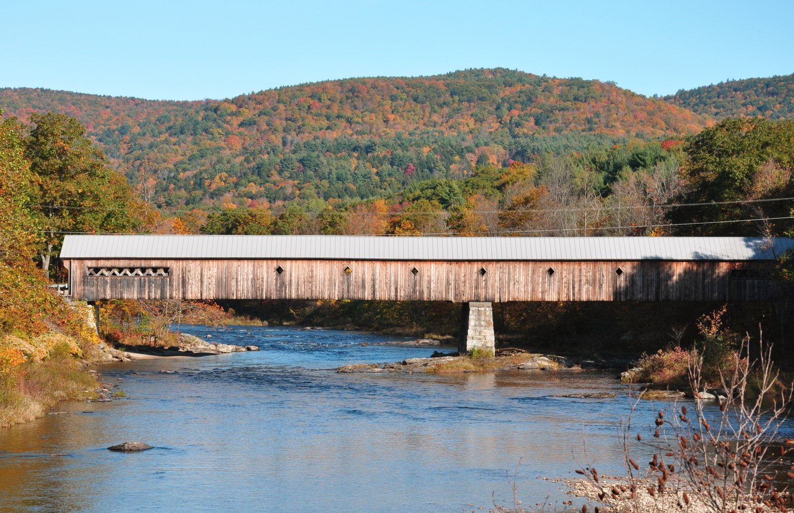 A Vermont covered bridge over a river in fall